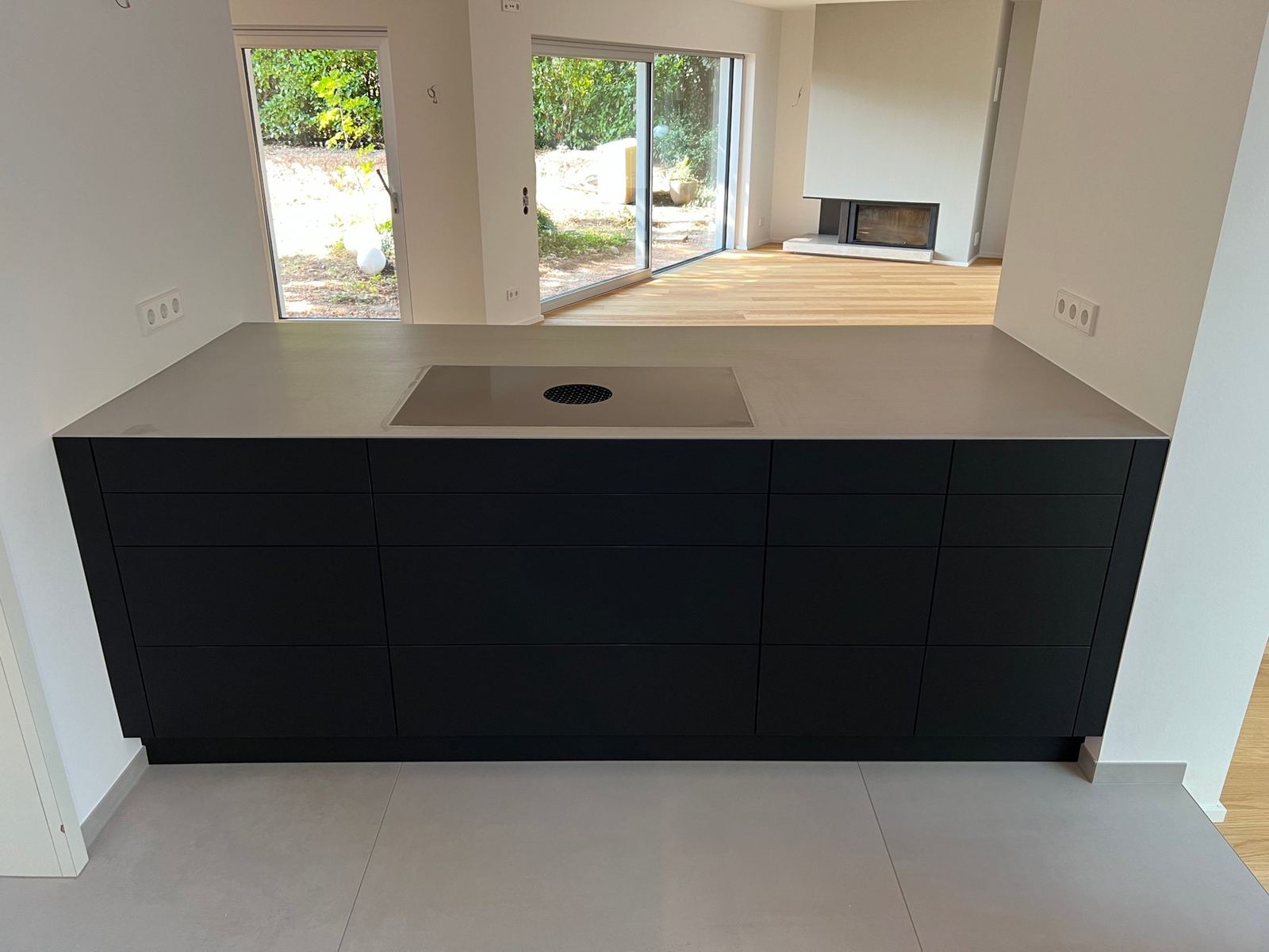 Kochinsel mit Edelstahl-Arbeitsplatte und Blick ins Wohnzimmer