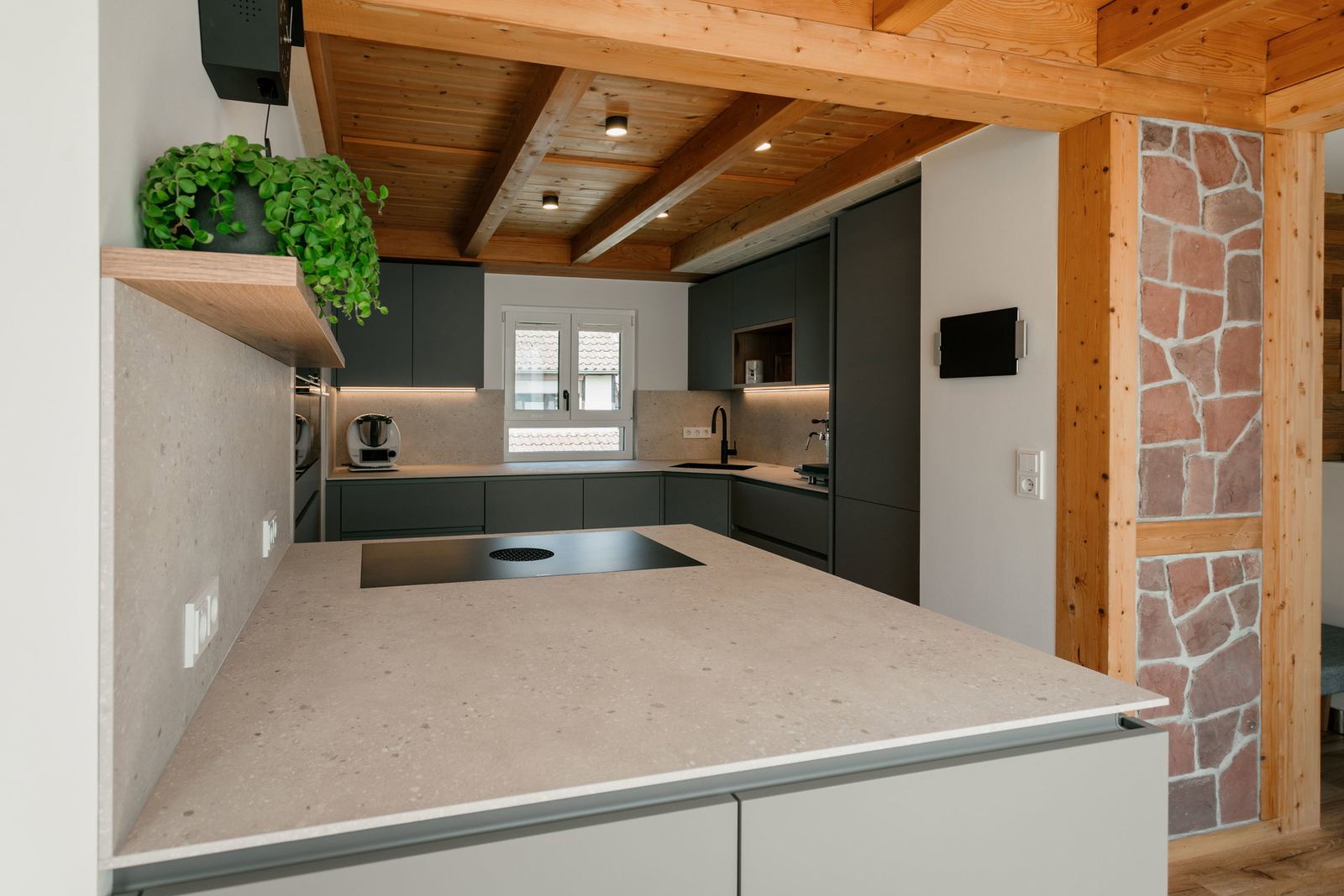 Küche mit Steinwand und Holzbalkendecke